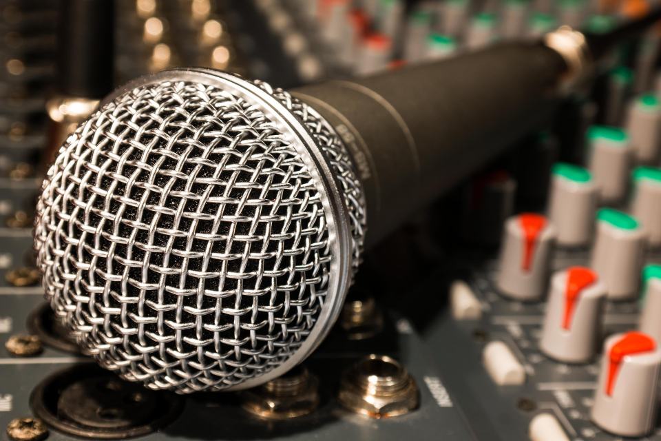 A microphone in front of a mixing desk
