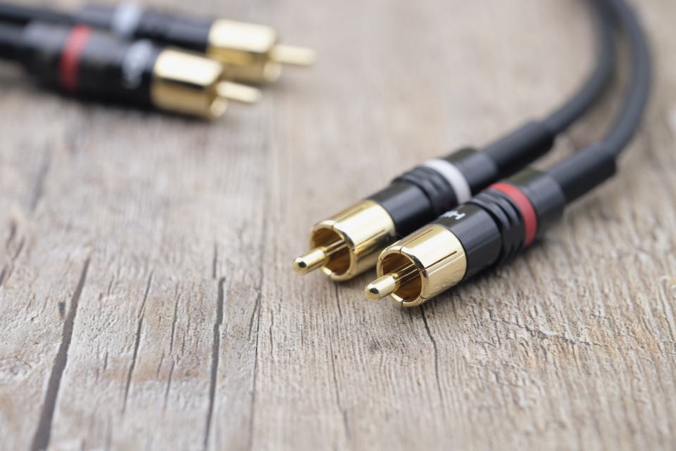 Gold-plated RCA audio plugs on a wooden table